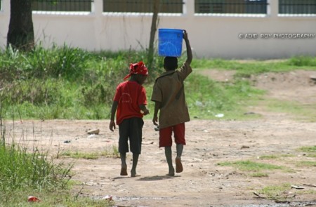 Two boys carrying a bucket of water to their home from the water well in the small town of Tabora in Tanzania, East Africa. ©Adib Roy